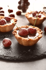 Tasty tartlets with cherries on slate plate, closeup