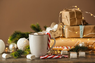 Cup of delicious hot cocoa with marshmallows and candy canes on wooden table