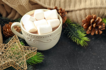 Cup of hot cocoa with marshmallows and Christmas decorations on table
