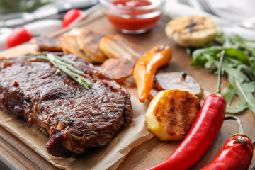 Tasty grilled meat with vegetables and herbs on board