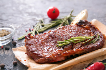 Tasty grilled meat with herbs and spices on grunge table