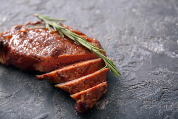 Tasty cut grilled meat with herbs on grunge table