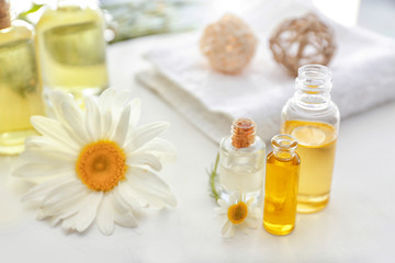 Bottles of essential oil with chamomile flowers on white board