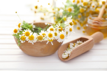 Obraz na płótnie Canvas Bowl with chamomile flowers on wooden table