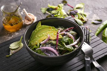 Bowl with healthy vegetable salad on wooden board