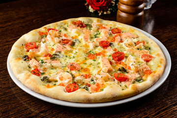 Tasty warm pizza with fish, tomatoes, cheese and caviar on the t