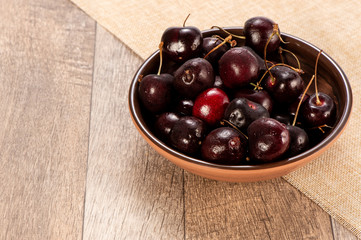 fresh cherry in wood bowl on wooden background 