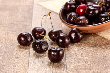 fresh cherry in wood bowl on wooden background 