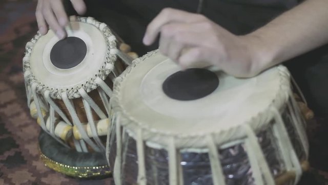 A medium shot of a Caucasian male playing Indian tabla drums.
4X slowed down
