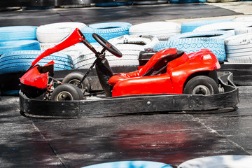 Old red kart against the tires on the kart track