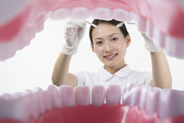 歯科器具を持って歯の治療をする白衣を着た女性
