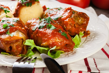 Stuffed cabbage with meat and rice served with boiled potatoes and tomato sauce