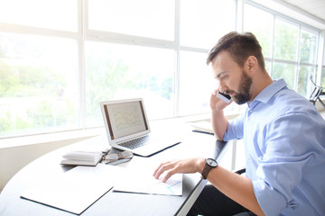 Naklejka premium Businessman talking by phone while working in office