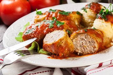 Stuffed cabbage with meat and rice served with boiled potatoes and tomato sauce