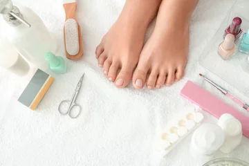 Fototapeten Feet of young woman and set for pedicure on white towel © Pixel-Shot