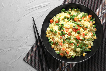 Tasty rice with vegetables on plate, top view