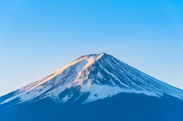 Fotobehang Close-up of Mount Fuji view with Lake Kawaguchi and clear blue sky background in Kawaguchiko, Japan Peak of Fuji mountain cover with snow and shading with golden sunlight in the morning © Hathaichanok