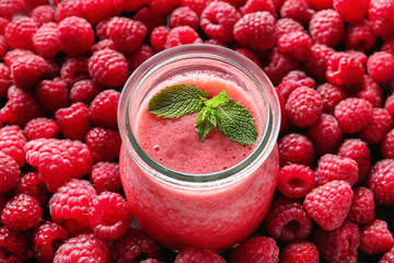 Glass jar with tasty raspberry smoothie on berries
