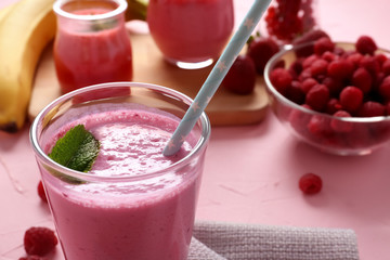 Glass with tasty raspberry milkshake on table, closeup