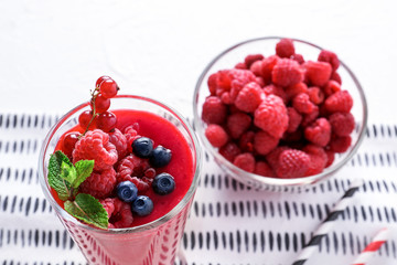 Glass cup with tasty berry smoothie on table