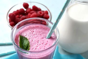Glass with tasty raspberry milkshake on table, closeup