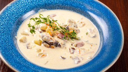 The concept of Italian cuisine. Creamy soup with seafood, mussels, potatoes, carrots, thyme. serve in a blue plate.