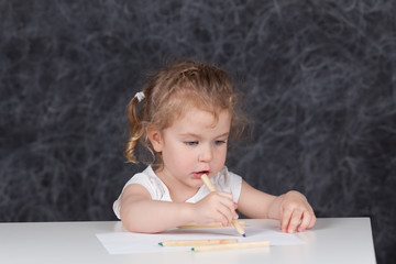 Little girl draws with pencils, portrait on background of school board