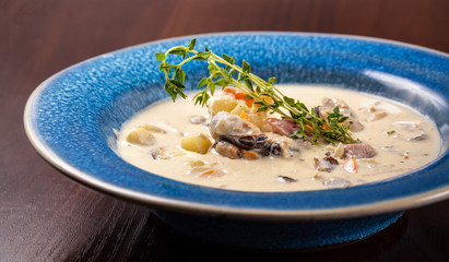 The concept of Italian cuisine. Creamy soup with seafood, mussels, potatoes, carrots, thyme. serve in a blue plate.