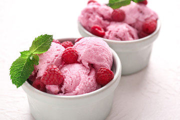 Bowls with tasty raspberry ice-cream on white background, closeup
