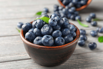 Bowl with ripe blueberries on wooden table