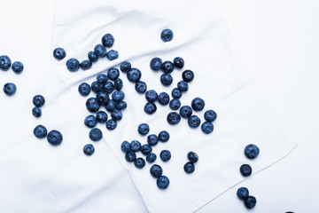 Fresh blueberries scattered on a white napkin, top view