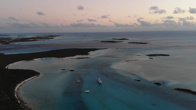 Aerial sunset displaying turquoise blue ocean water, sand bars, yachts, and small islands in the Bahamas. Drone video from DJI Mavic Air.