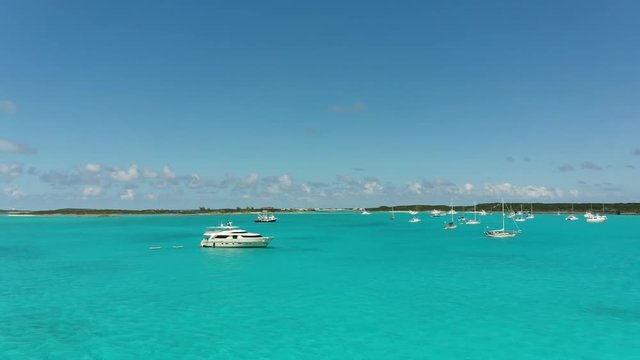 Beautiful turquoise blue, clear water of island harbor in the Bahamas. Group of sailboats, yachts, and motor boats.