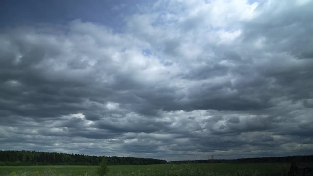 Timelapse of a cloudy sky above big grass field.