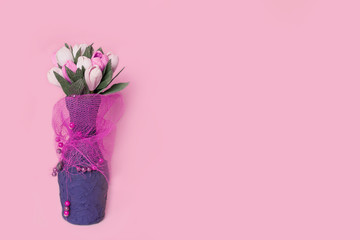 Handmade vase with a bouquet of flowers. Decorative interior vase. Gently pink background.