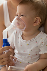 Baby taking respiratory inhalation therapy. Mother holding the mask of a nebuliser