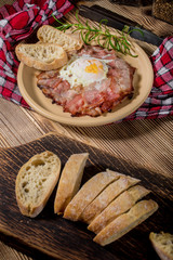 Plate of breakfast with fried eggs, bacon and bread.
