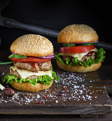 two burgers with a meat chop, vegetables and green lettuce
