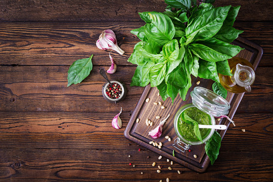 Homemade pesto sauce fresh basil, pine nuts and garlic on wooden background. Italian food. Top view. Flat lay