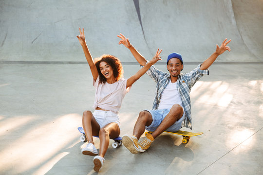Portrait of a happy young african couple with skateboard