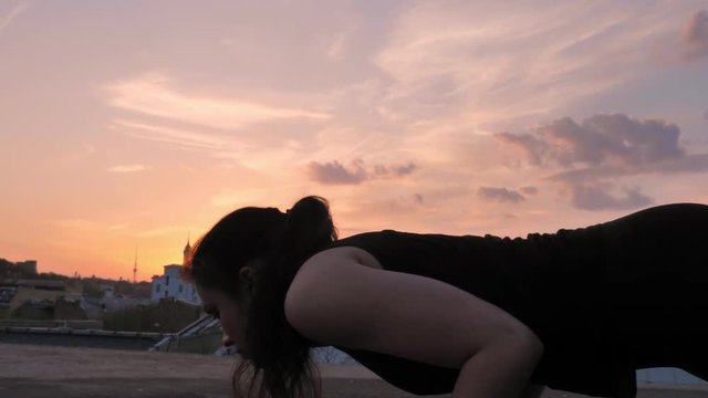 Yogi girl is standing in cobra pose on rooftop in summer on sunset, healthy lifestyle, relax concept, sport concept