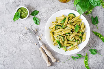 Penne pasta with  pesto sauce, zucchini, green peas and basil. Italian food. Top view. Flat lay.