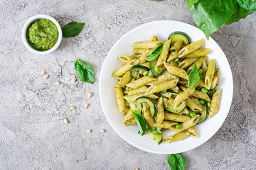 Penne pasta with  pesto sauce, zucchini, green peas and basil. Italian food. Top view. Flat lay.