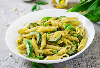 Penne pasta with  pesto sauce, zucchini, green peas and basil. Italian food.