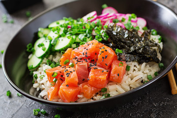 Hawaiian salmon fish poke bowl with rice, radish,cucumber, tomato, sesame seeds and seaweeds. Buddha bowl. Diet food