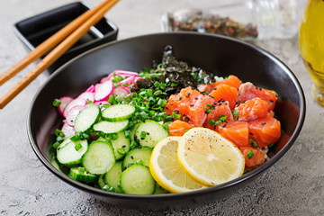 Hawaiian salmon fish poke bowl with rice, radish,cucumber, tomato, sesame seeds and seaweeds. Buddha bowl. Diet food