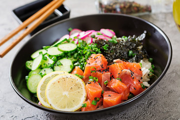 Hawaiian salmon fish poke bowl with rice, radish,cucumber, tomato, sesame seeds and seaweeds. Buddha bowl. Diet food