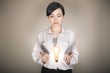手の間に電球を浮かべる若い女性