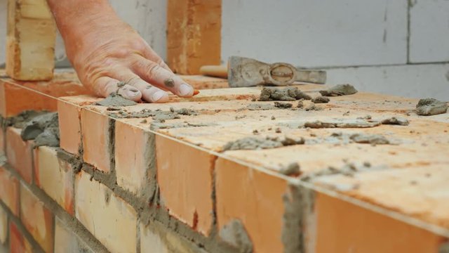 An experienced worker makes a brick wall masonry