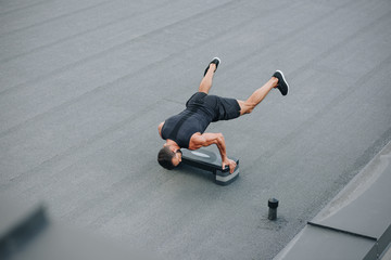 high angle view of sportsman training with step platform and standing on hands on roof